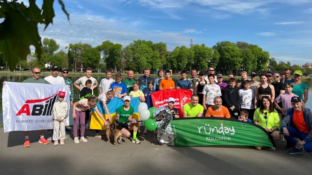 Runday Kolomyia community group by the lake with Ukrainian flag